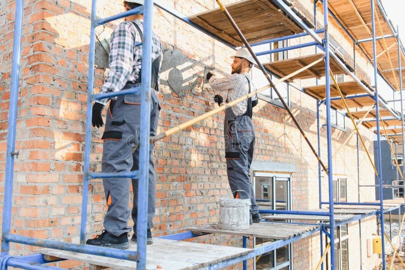Construction workers applying stucco to an exterior wall