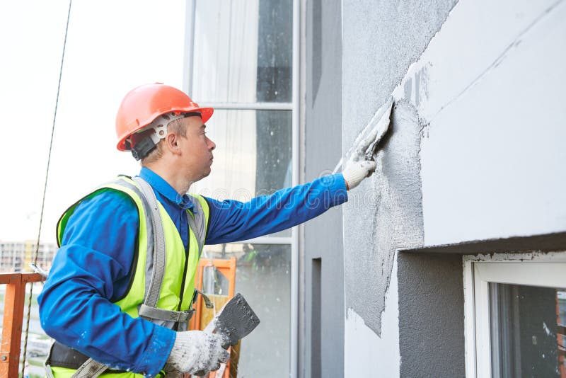 Worker plastering exterior facade of building